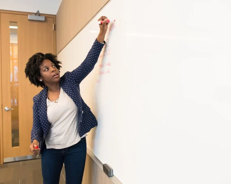 woman writing formula on whiteboard